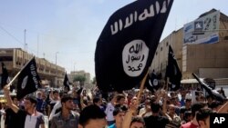 FILE - Demonstrators chant pro-Islamic State group slogans as they carry the group's flags in front of the provincial government headquarters in Mosul, Iraq, June 16, 2014.