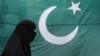 A woman clad in a burqa walks past the national flag of Pakistan, which is being displayed for sale ahead of Pakistan's Independence Day, in Lahore August 13, 2011. Pakistan commemorates its Independence Day on August 14. REUTERS/Mohsin Raza (PAKISTAN - T