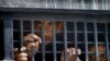 FILE - Detainees peer out from a prison van after their court appearance in Islamabad, Pakistan, Sept. 13, 2014. 