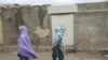 Local women walk past the locked house 