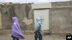 Local women walk past the locked house 