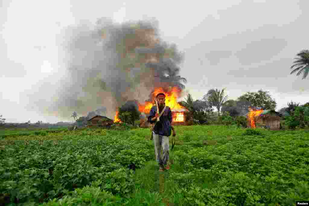 10/6/2012: Người đàn ông sắc tộc Rakhine trang bị vũ khí thô sơ, bỏ đi sau khi nhiều căn nhà bị đốt trong vụ xô xát giữa người Rakhine theo Phật giáo và người Rohingya theo Hồi giáo trong tỉnh Sittwe, Miến Điện.